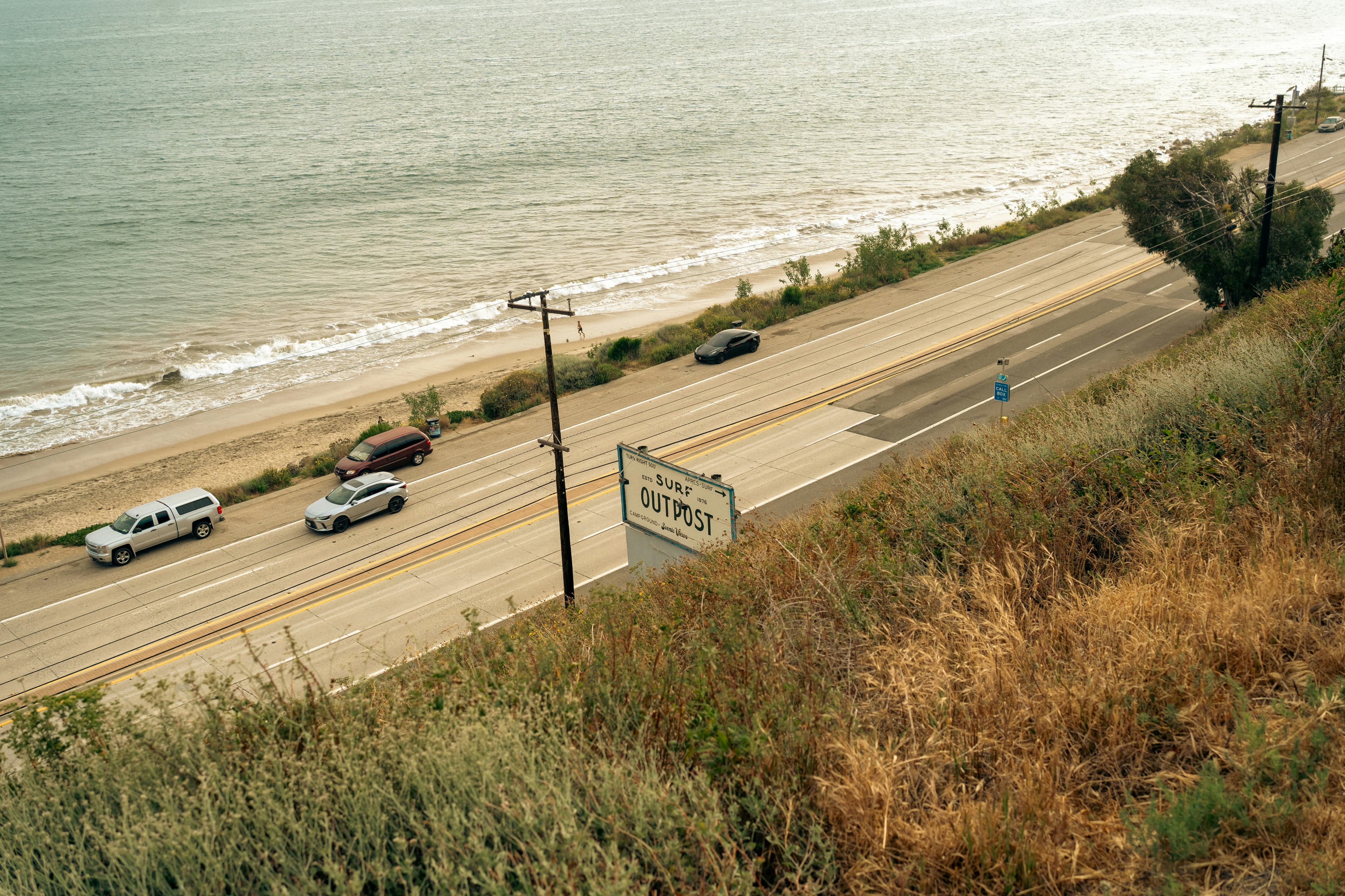 Cars driving along a scenic coastal highway with the ocean stretching out beside the road